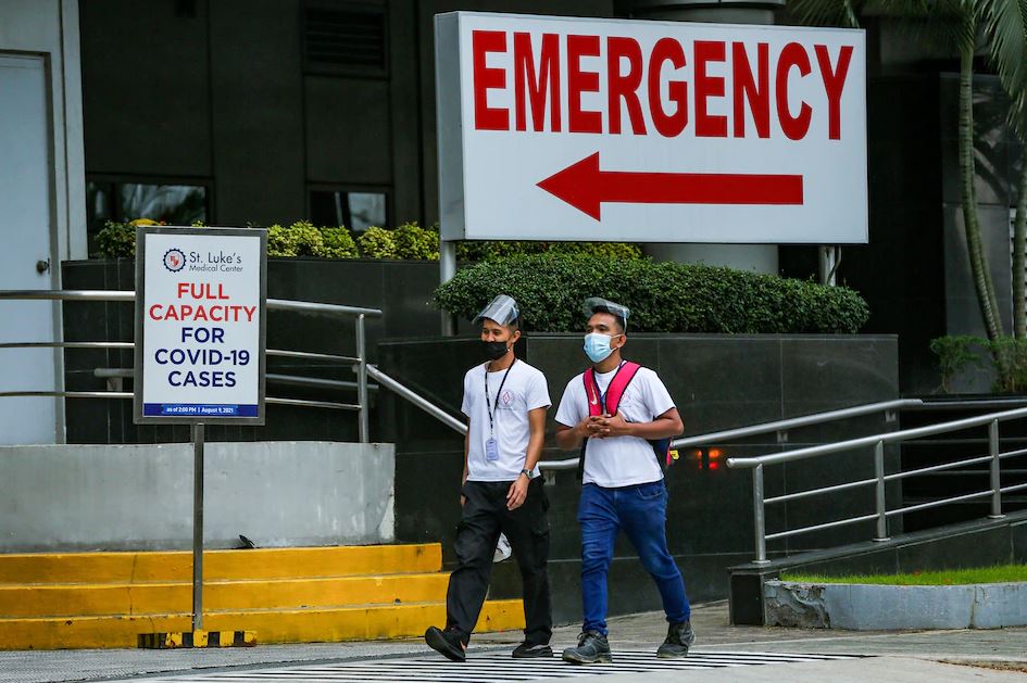 People pass in front of an announcement for the St. Luke’s Hospital at the Bonifacio Global City (BGC) in Taguig City on August 10, 2021. Jonathan Cellona, ABS-CBN News